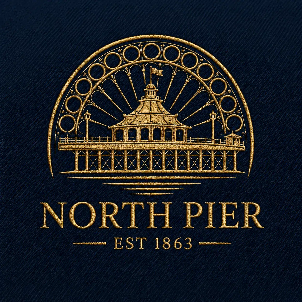 The North Pier emblem embroidered in gold thread on navy fabric